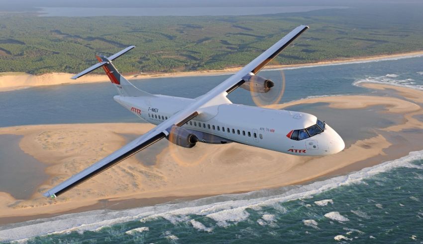 A white airplane flying over a sandy beach.