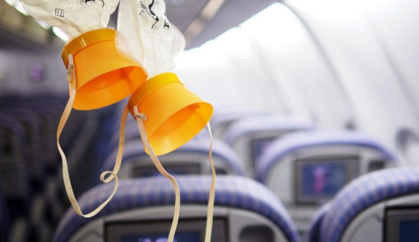 A pair of orange hats hanging from the ceiling of an airplane.