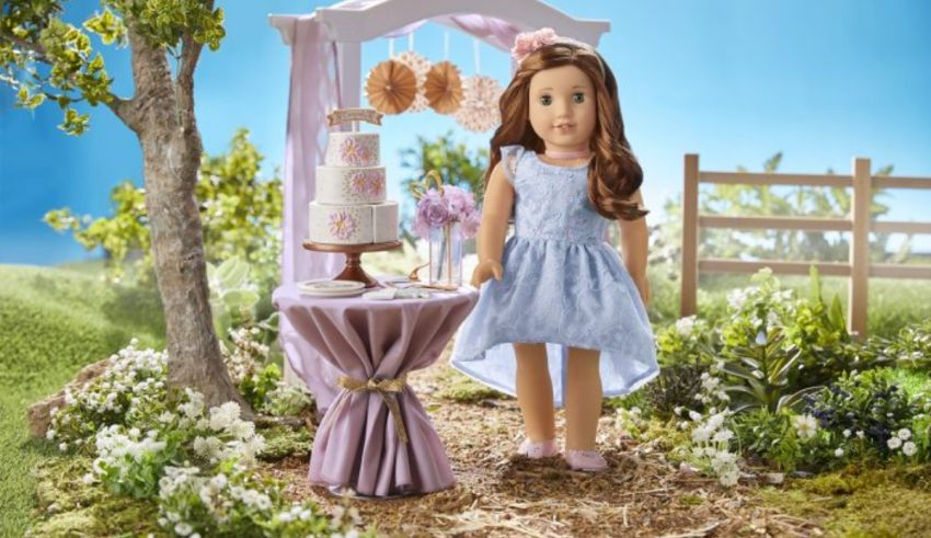 A doll is standing in a garden with a cake.