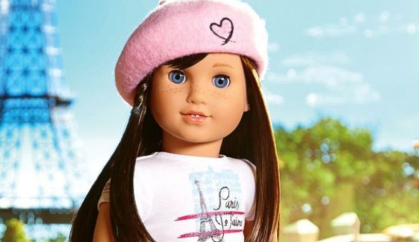 An american girl doll in a pink hat in front of the eiffel tower.