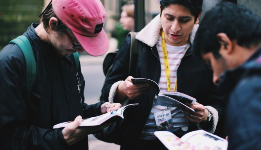 A group of people looking at a book on a street.