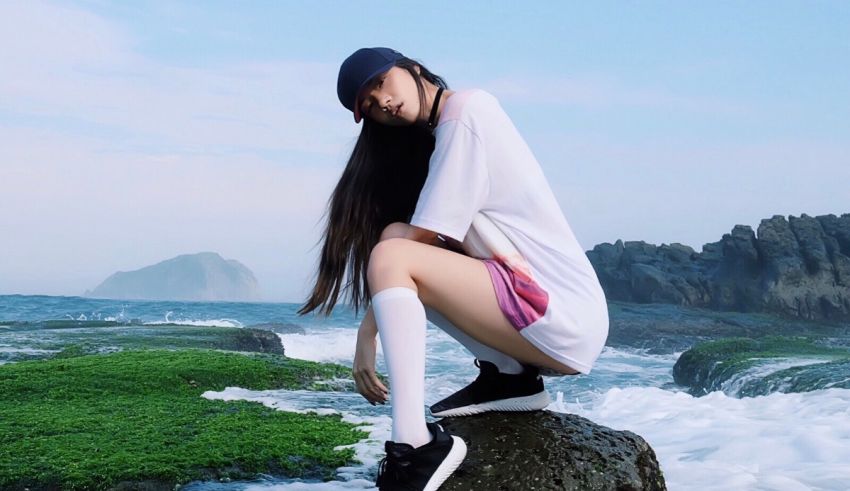 A girl sitting on a rock next to the ocean.