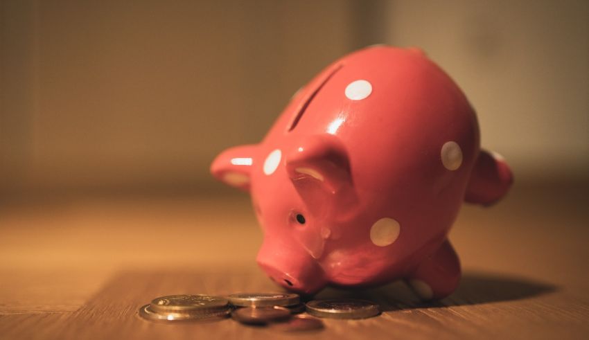 A pink piggy bank sitting on top of a pile of coins.