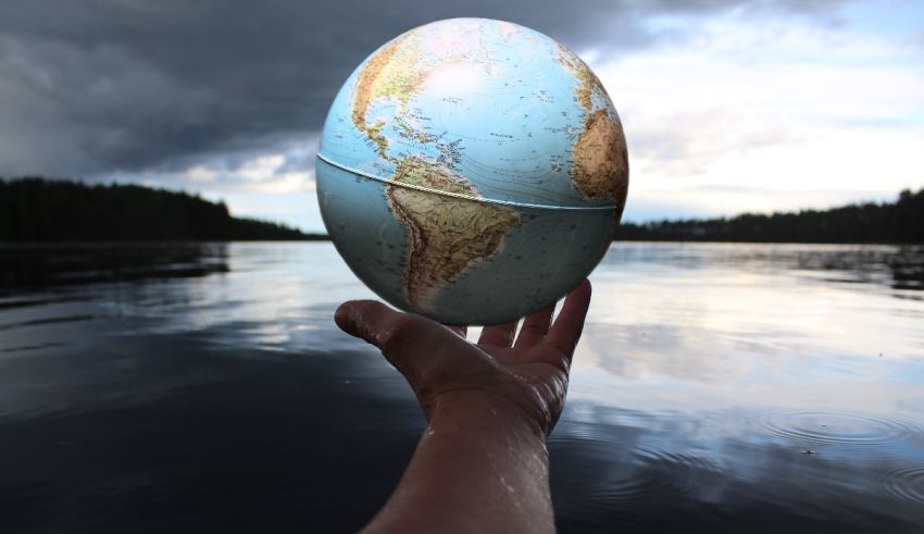 A person holding a globe over a body of water.