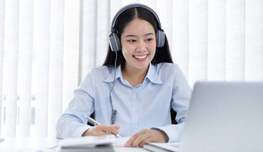 Asian woman in headphones working at a desk.