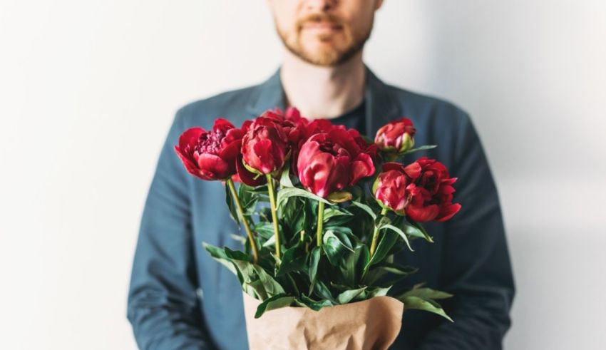 A man holding a bouquet of red flowers.