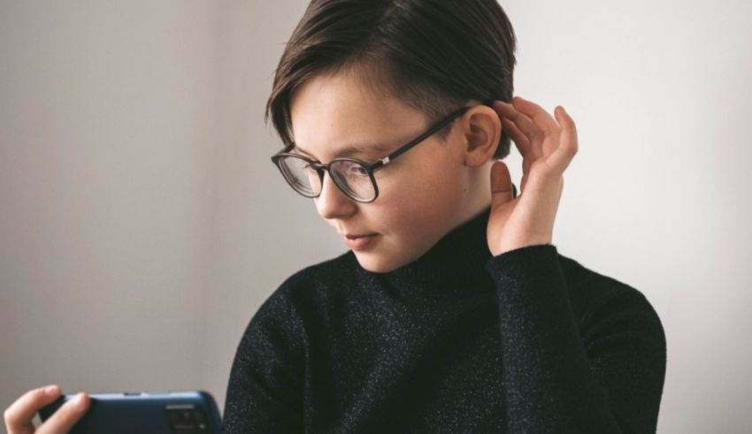 A boy wearing glasses is looking at his phone.