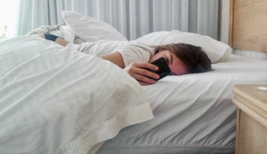 A man sleeping in bed with a cell phone.