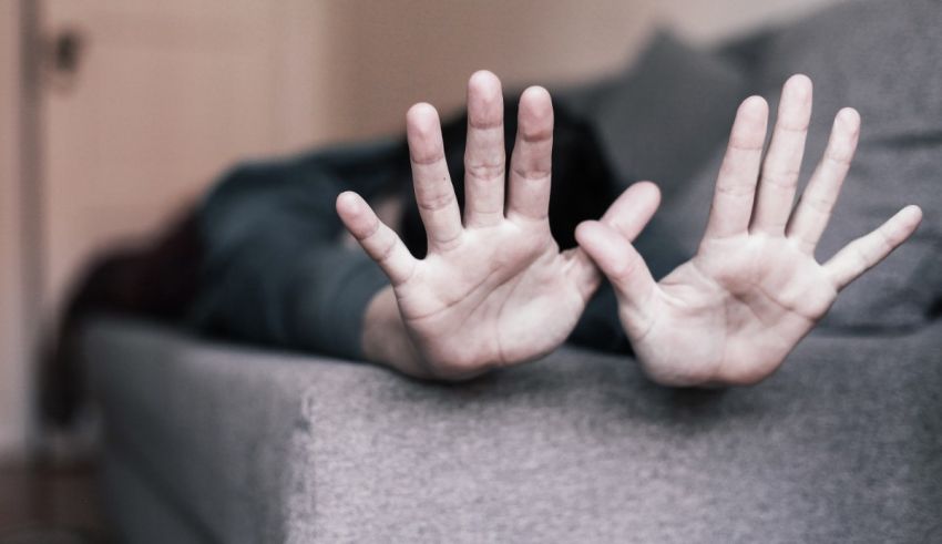 A person laying on a couch with their hands up.