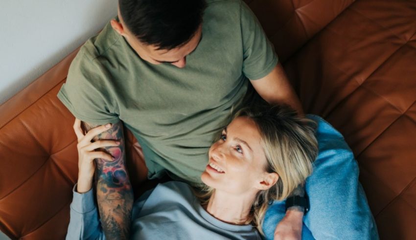 A man and woman laying on a couch with tattoos.