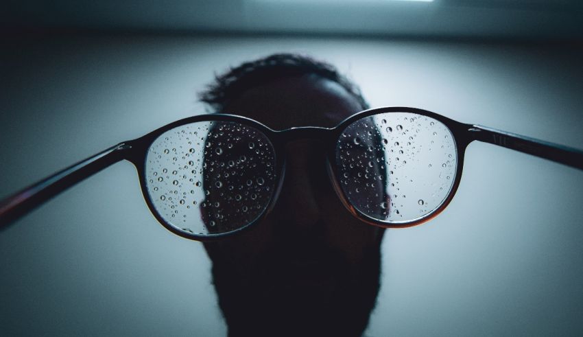 A man wearing glasses with water droplets on them.