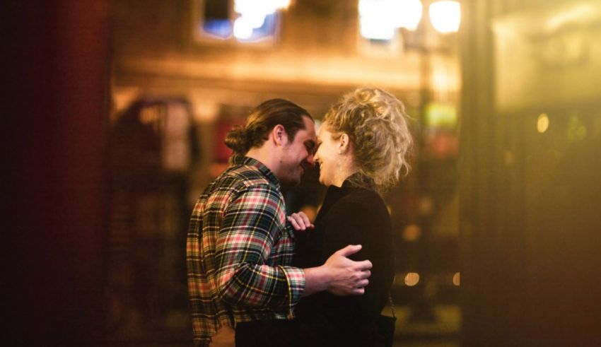 A couple embracing in front of a building at night.