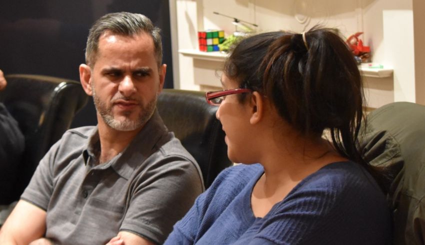 A man and woman sitting on a couch talking to each other.