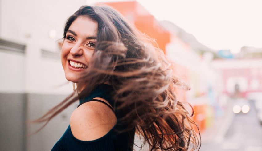 A woman smiling with her hair blowing in the wind.