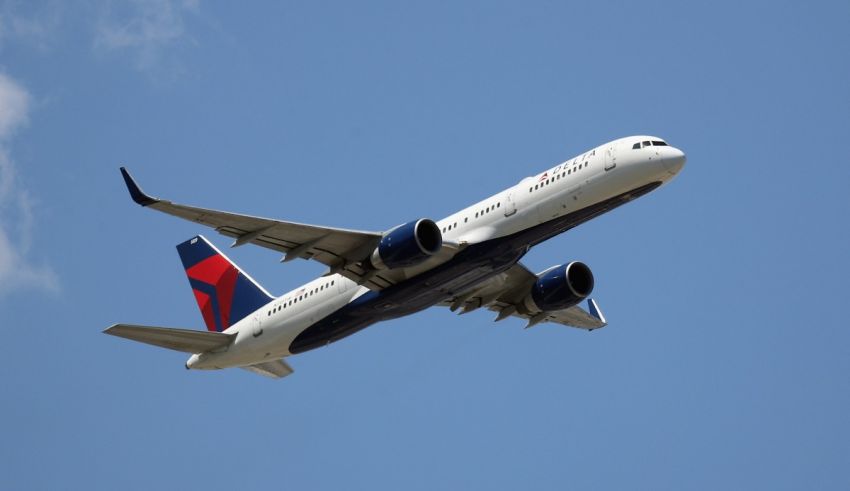 A delta airplane flying through a blue sky.