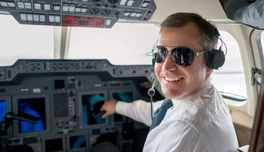 A man in sunglasses sitting in the cockpit of an airplane.