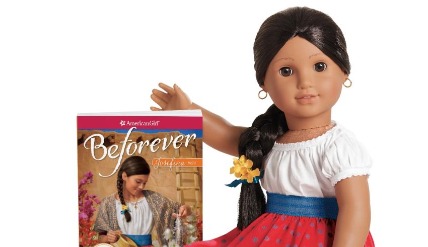 An american girl doll with a book next to it.