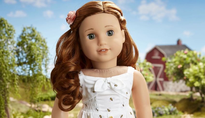 An american girl doll in a white dress standing in a field.
