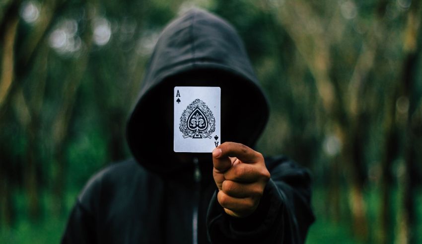 A person in a hoodie holding up a playing card.