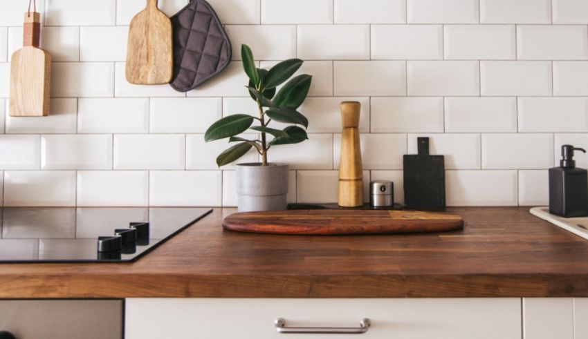 A kitchen counter with a potted plant and a wooden board.