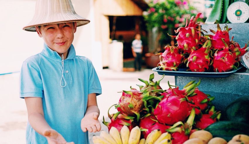 A boy is standing in front of a display of fruit.