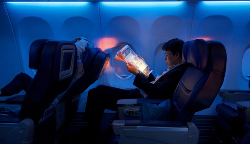 A man is reading a book on an airplane.