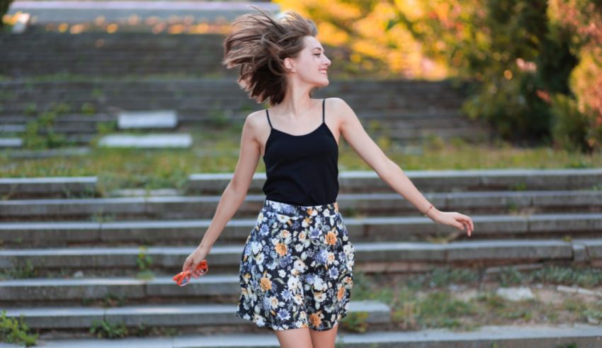 A woman in a floral skirt is dancing on steps.