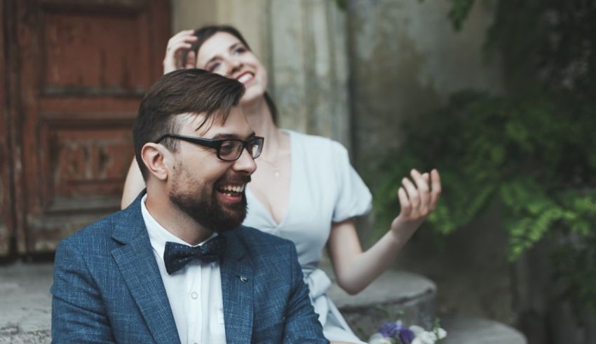 A man in a suit and a woman in a dress sitting on steps.