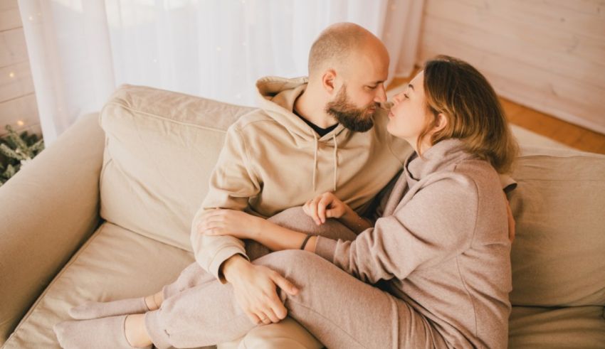 A couple is sitting on a couch and kissing each other.