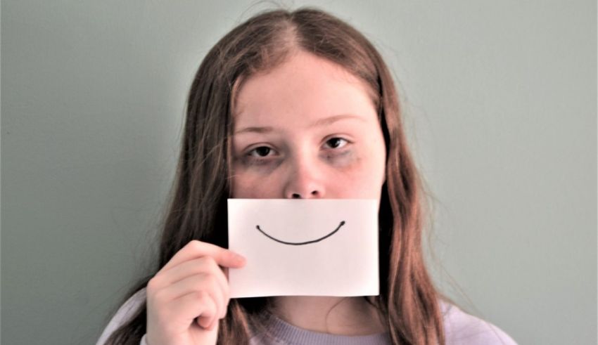 A girl holding a piece of paper with a smiley face on it.