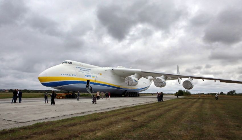 A large airplane on a runway with people standing around it.