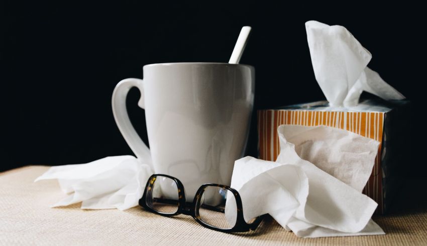 A cup of coffee, tissue and glasses on a table.