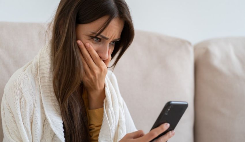 A woman is looking at her phone while sitting on the couch.