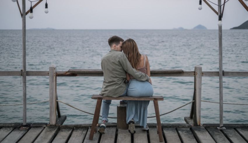 A couple sitting on a bench overlooking the ocean.