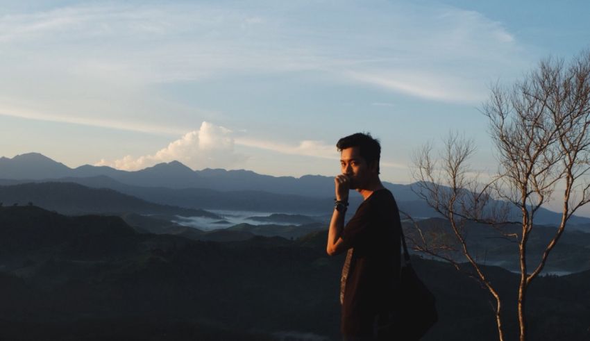 A man standing on top of a hill with mountains in the background.