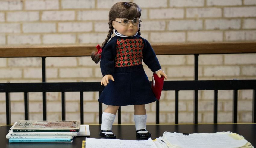 A doll sitting on a table next to books.