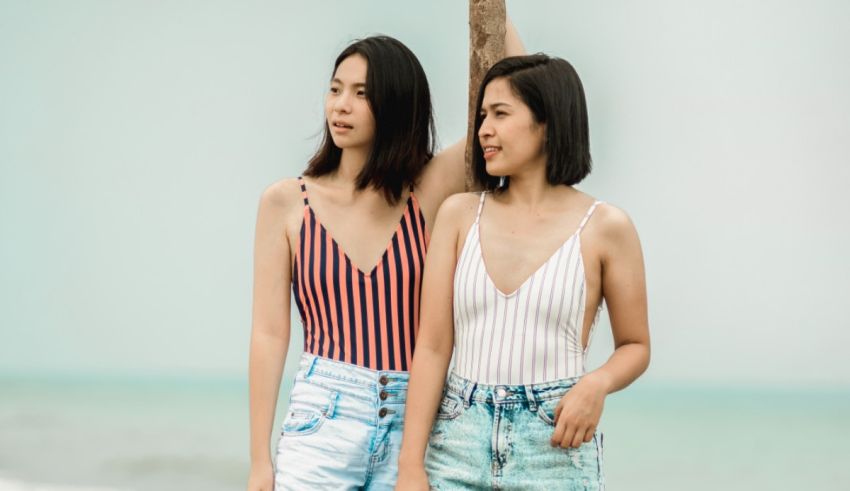 Two young women standing next to each other on the beach.