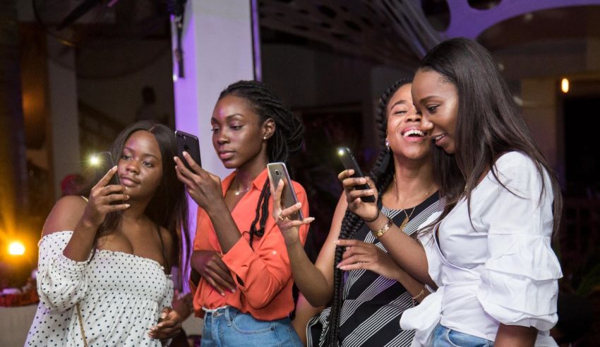 A group of young women looking at their phones at a party.