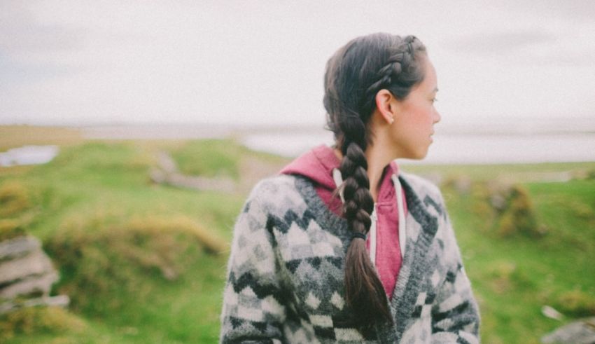 A girl with braided hair standing in a field.