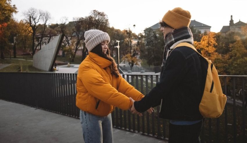 A man and woman are holding hands in front of a bridge.