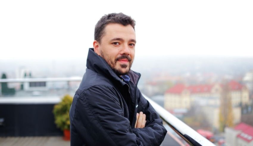 A man with a beard standing on a balcony.