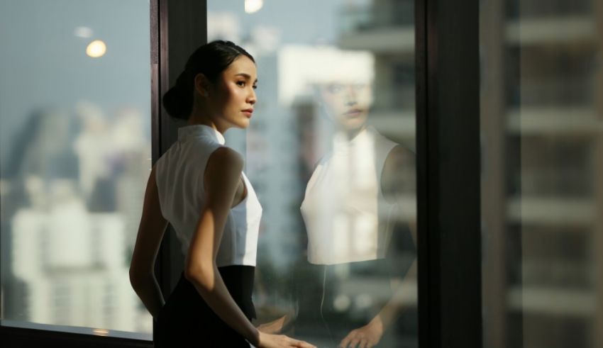 A woman in a black dress is looking out of a window.