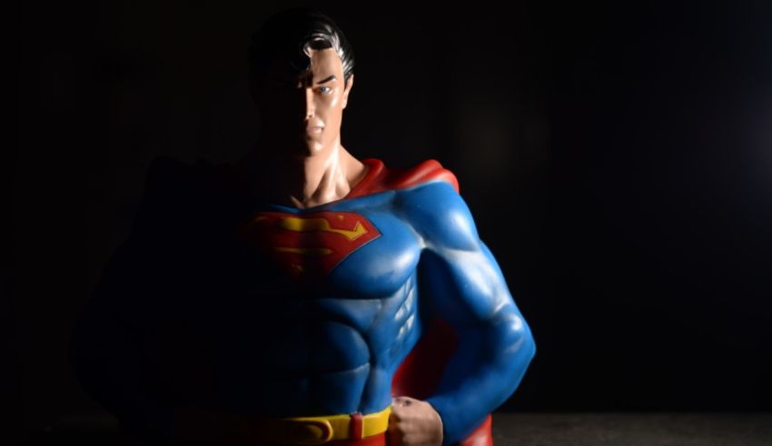 A statue of superman standing in front of a dark background.
