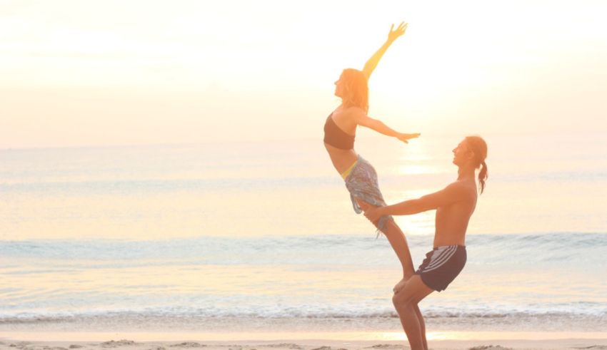 A man holding a woman on his hands on a beach.