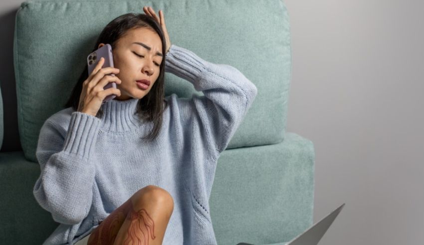 A woman is sitting on a couch and talking on her phone.