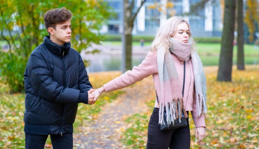 A young man and woman holding hands in a park.