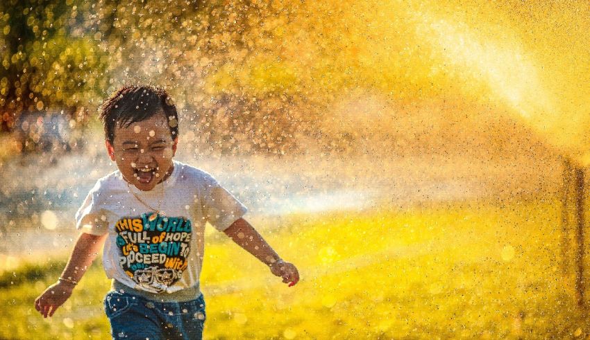 A young boy running through a sprinkler.