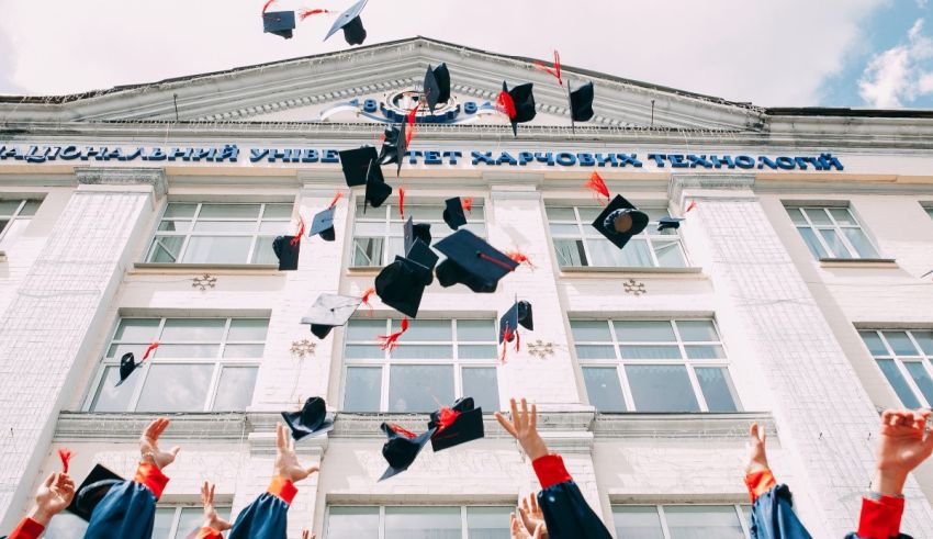 Graduates tossing their caps in the air in front of a building.
