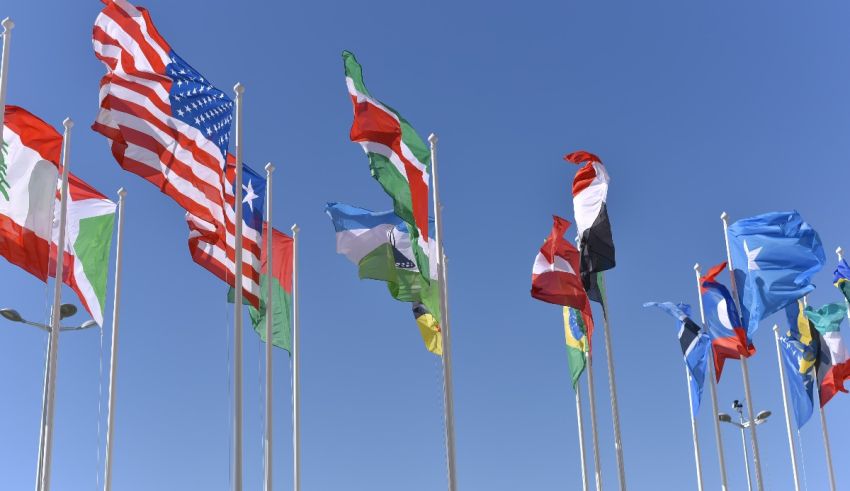 A group of flags flying in the wind against a blue sky.