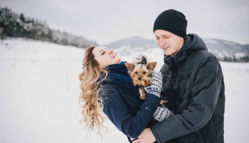 A couple holding a dog in the snow.